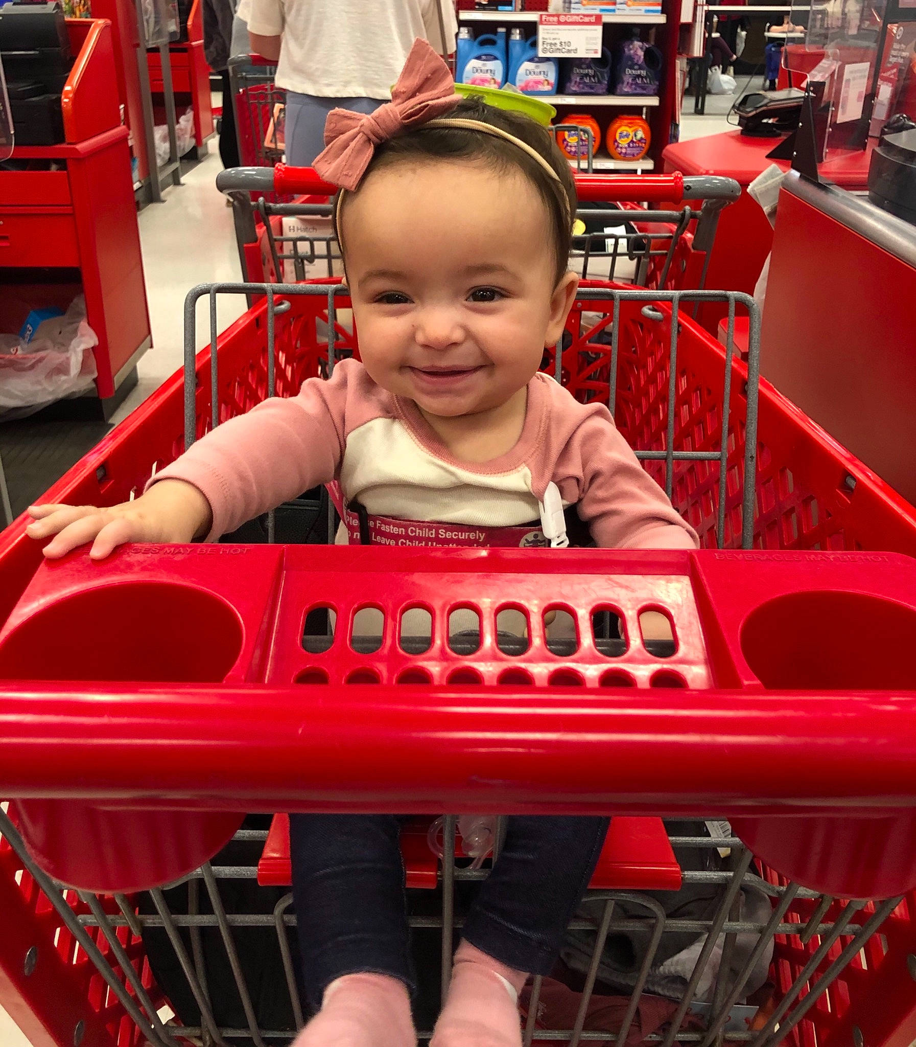 Rainey is registered to the contest to win money with this photo: baby_toddler_clothing, cart, chair, city, customer, fun, happy, joy, leisure, magenta, motor_vehicle, person, play, recreation, red, shelf, shopping_cart, sitting, smile, t_shirt