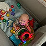 Messiah is registered to the contest to win money with this photo: baby, infant, child, playpen, toys, toy_balls, colorful, smiling, sitting, indoor, nursery, playtime, stuffed_animal, activity_center, blanket, mattress, portrait, looking_up, happy, safe