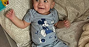 Messiah joined the competition — help win amazing prizes! baby, child, infant, smiling, happy, portrait, playpen, indoors, lying_down, seated, mickey_mouse, clothing, romper, gray_outfit, blanket, pillow, toy, nursery, soft_furnishings, closeup