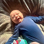 Grayson joined the competition — help win amazing prizes! baby, smiling, blue_outfit, blanket, cozy, texture, soft, sunlight, happy, infant, lying_down, cute, child, indoors, warm_light, blanket_pattern, comfort, portrait, playful, relaxed