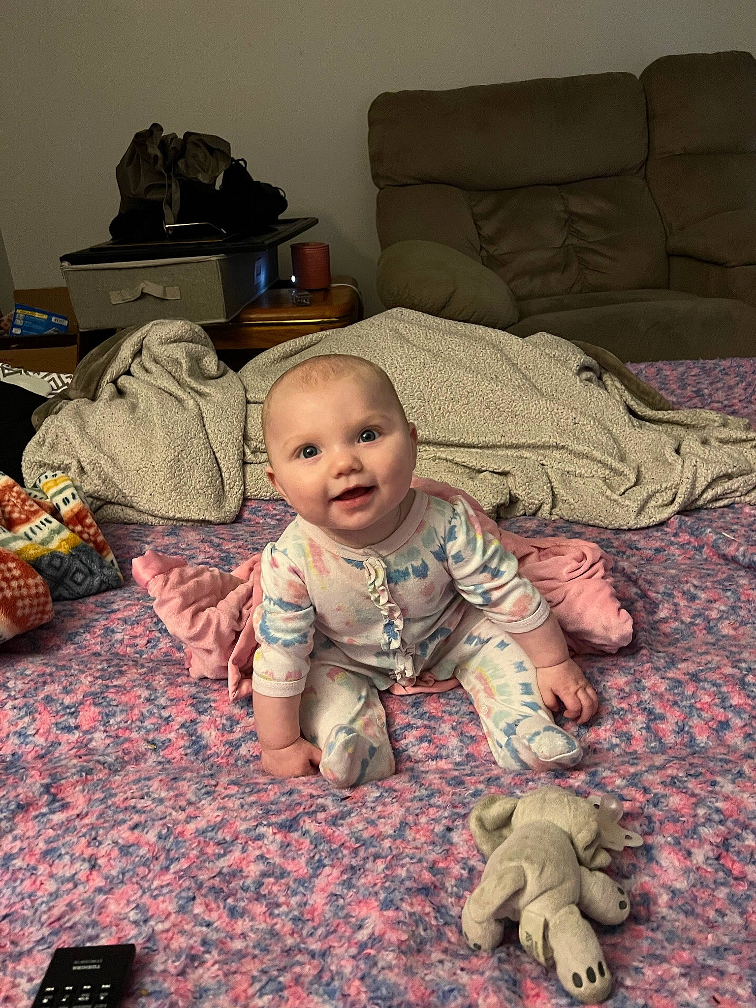 Maylee is registered to the contest to win money with this photo: baby, baby_toddler_clothing, backpack, bag, cheek, child, comfort, couch, floor, flooring, hardwood, head, living_room, luggage_and_bags, mammal, person, room, sitting, smile, toddler
