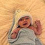 Theo is registered to the contest to win money with this photo: baby, towel, blanket, infant, smiling, cute, wrapped, soft_texture, hooded_towel, lying_down, skin, hand, face, expression, indoors, cozy, newborn, child, comfort, warmth