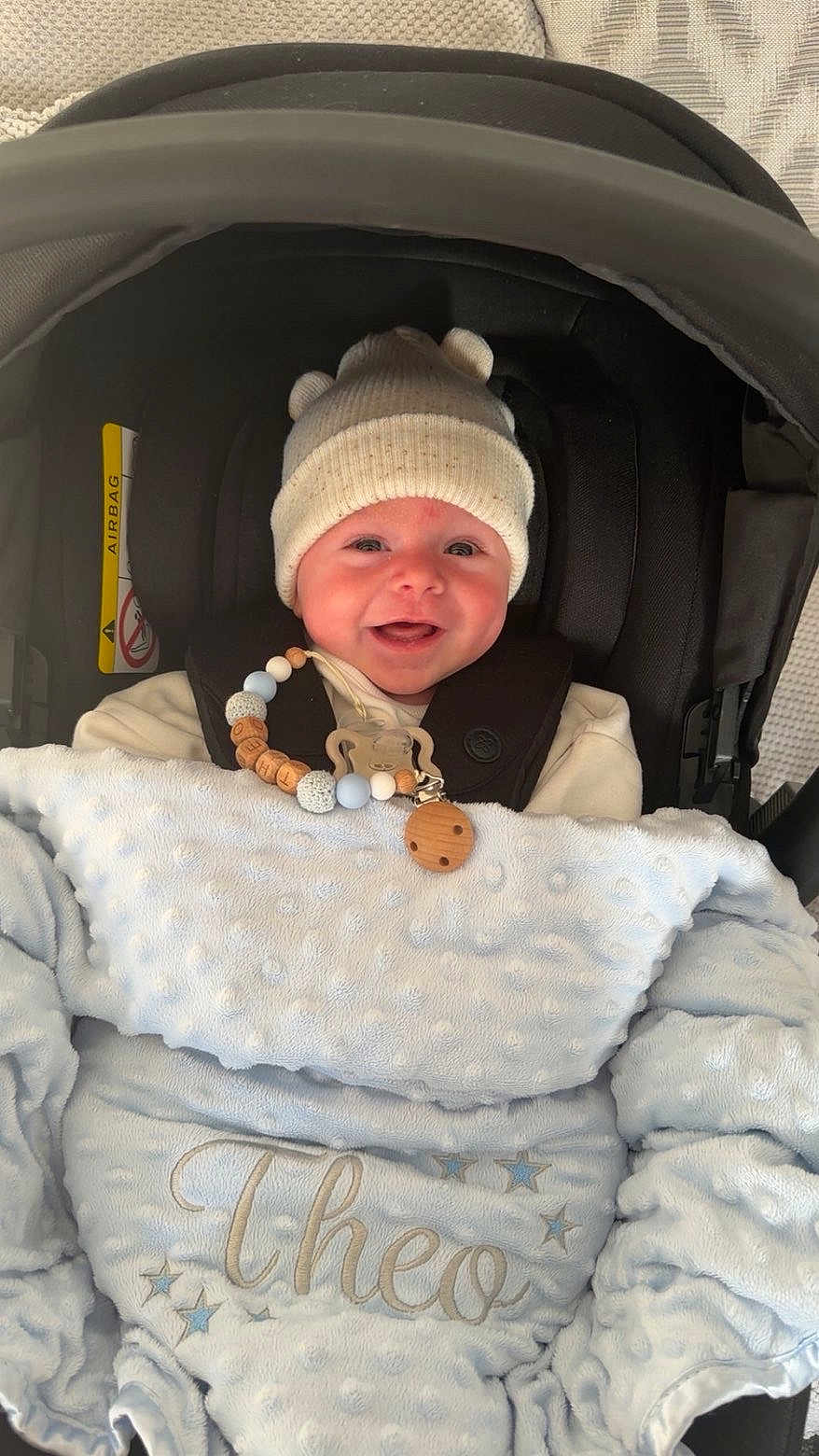 Theo joined the competition — help win amazing prizes! baby, infant, car_seat, blanket, hat, smiling, cute, pacifier_clip, beads, blue, white, face, child, clothing, happy, indoors, warm, cozy, person, portrait