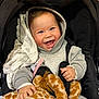 baby, child, smiling, hoodie, stroller, plush_toy, giraffe, toy, happy, face, hands, clothing, blanket, indoor, cute, infant, person, portrait, comfort, warm