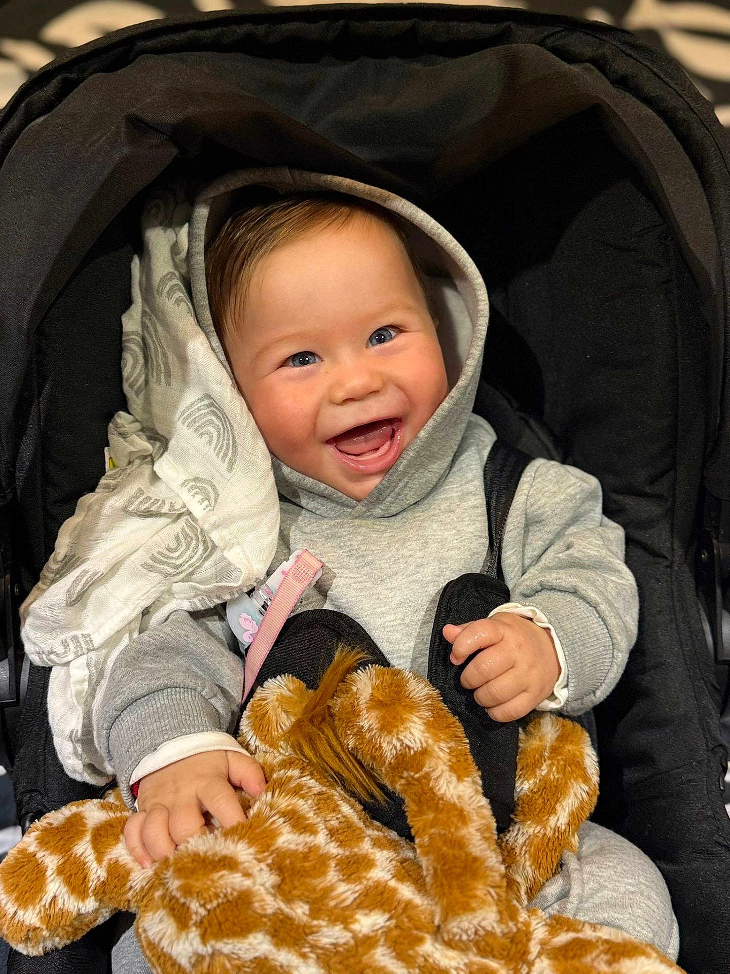 Mattias joined the competition — help win amazing prizes! baby, child, smiling, hoodie, stroller, plush_toy, giraffe, toy, happy, face, hands, clothing, blanket, indoor, cute, infant, person, portrait, comfort, warm