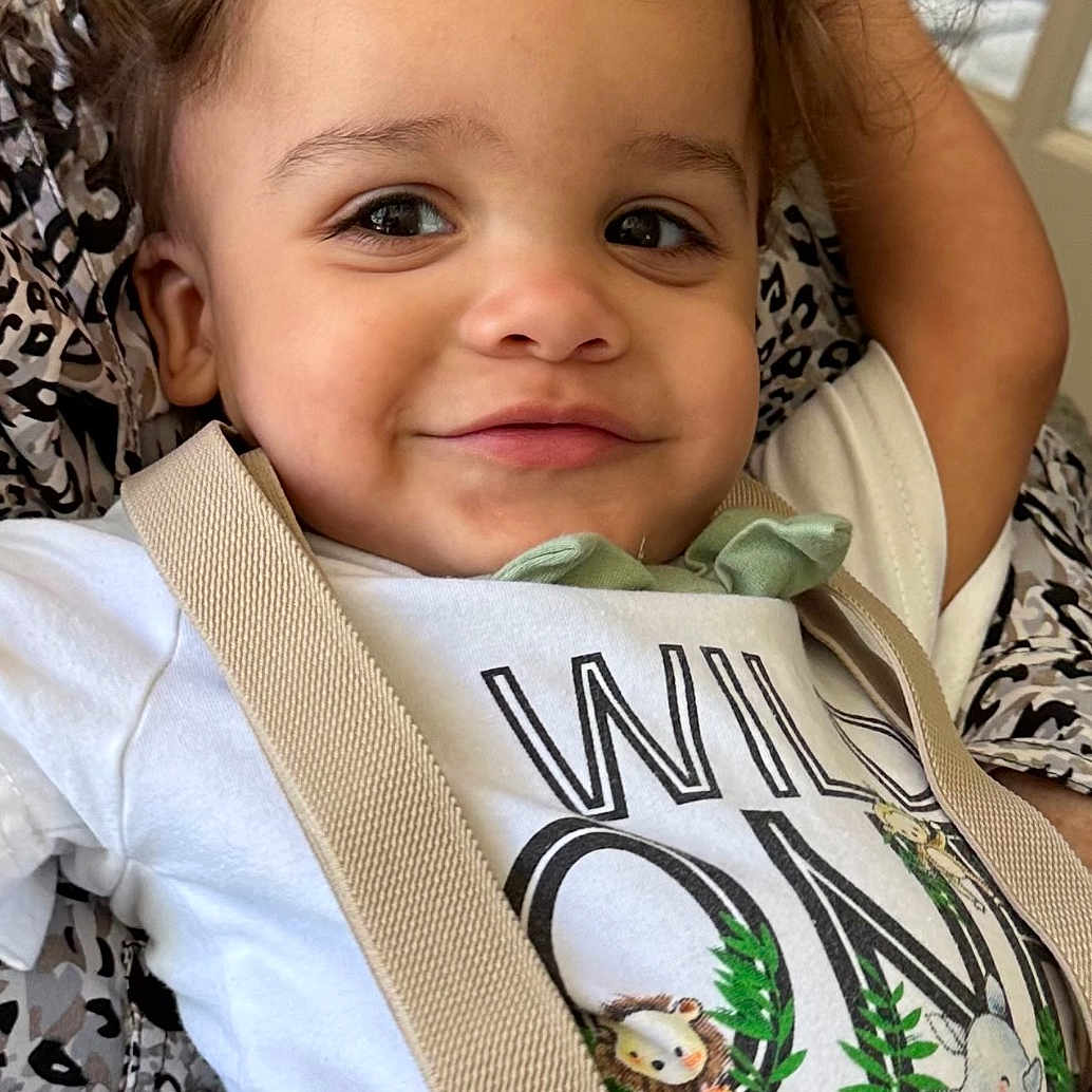 Rustyn is registered to the contest to win money with this photo: animal_print, child, closeup, clothing, curly_hair, cute, fabric, green_pants, happy, indoor, lion, pattern, person, portrait, resting, rhinoceros, shirt, smiling, suspenders, toddler