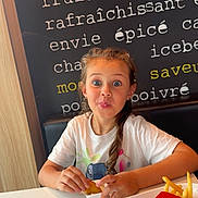 Lily-rose a rejoint le concours — aidez-le/la à gagner de superbes lots ! child, girl, fast_food, nugget, french_fries, tray, sauce, table, white_tshirt, brown_hair, dining, restaurant, playful_expression, food, indoor, seat, wall_text, casual_clothing, cute, eating