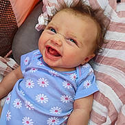 Harper is registered to the contest to win money with this photo: baby, child, smiling, laughing, blue_onesie, daisies, hair, blanket, striped, pink, white, face, happy, infant, cute, lying_down, skin, person, closeup, portrait