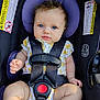 baby, child, car_seat, blue_eyes, safety_harness, floral_outfit, infant, seat_belt, purple_cushion, cute, portrait, baby_clothing, child_safety, straps, infant_seat, seat, young_child, baby_hands, face, person