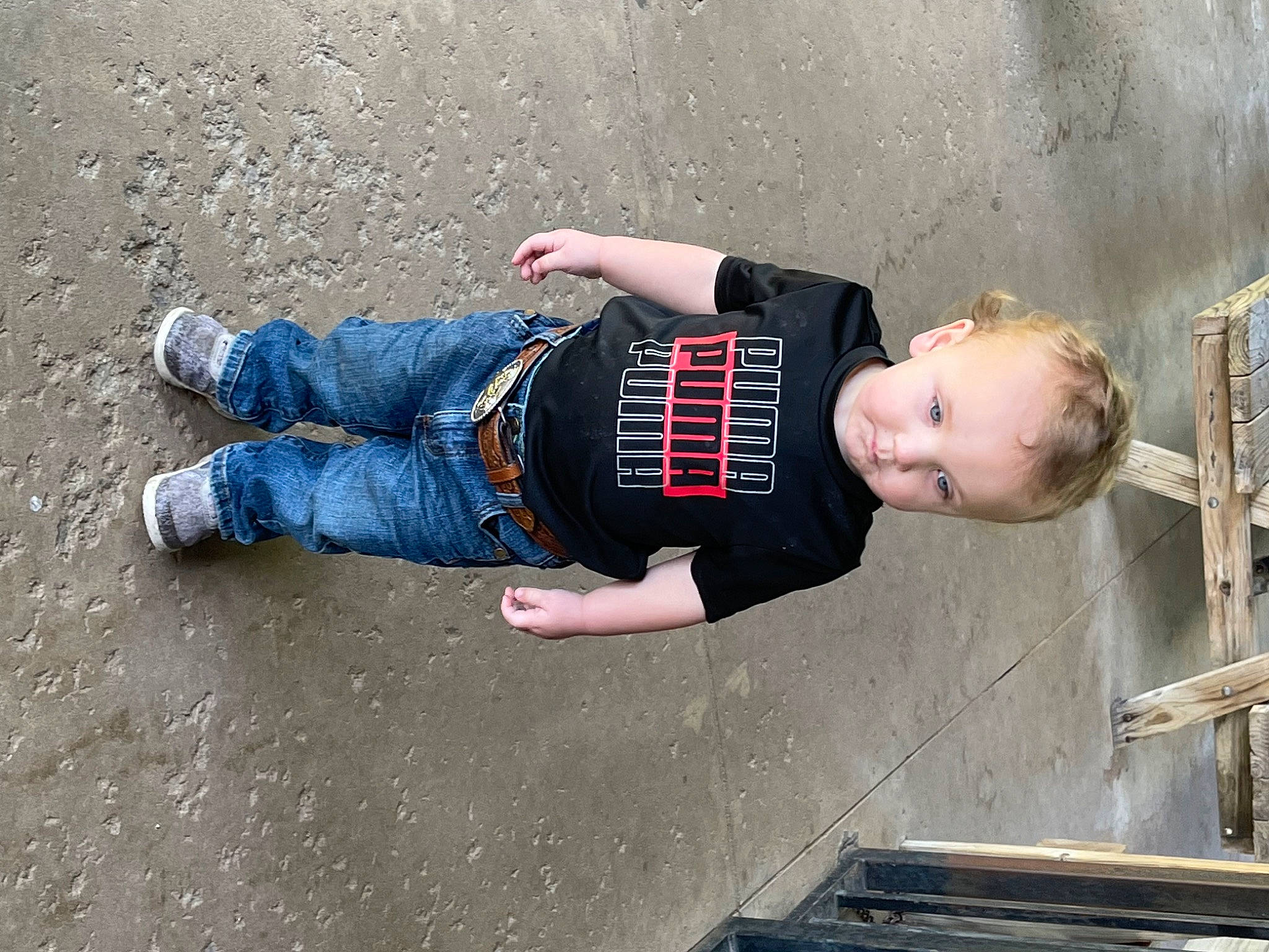 Leeland is registered to the contest to win money with this photo: asphalt, child, clothing, concrete, denim, elbow, electric_blue, foot, fun, human_leg, jeans, joint, leg, person, road_surface, sitting, t_shirt, toddler, waist, walking_shoe