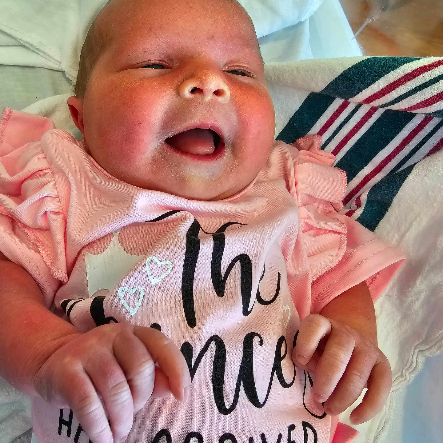 Elizabeth Kopkau is registered to the contest to win money with this photo: baby, newborn, pink_shirt, smiling, infant, clothing, blanket, hand, face, skin, cute, lying_down, happy, child, person, portrait, indoor, soft_texture, fabric, closeup