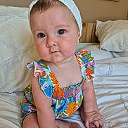 Léa participe au concours pour gagner de l'argent avec cette photo : baby, child, infant, headband, colorful_dress, sitting, bed, pillow, indoor, portrait, cute, hands, feet, skin, face, eyes, photography, room, decor, framed_photos