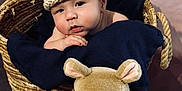 Caleb joined the competition — help win amazing prizes! baby, basket, knit_hat, blanket, plush_toy, glasses, yellow_sweater, blue_pants, soft_toy, cute, child, indoors, portrait, smiling, infant, cozy, woven, person, hat, resting