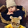 baby, basket, knit_hat, blanket, plush_toy, glasses, yellow_sweater, blue_pants, soft_toy, cute, child, indoors, portrait, smiling, infant, cozy, woven, person, hat, resting