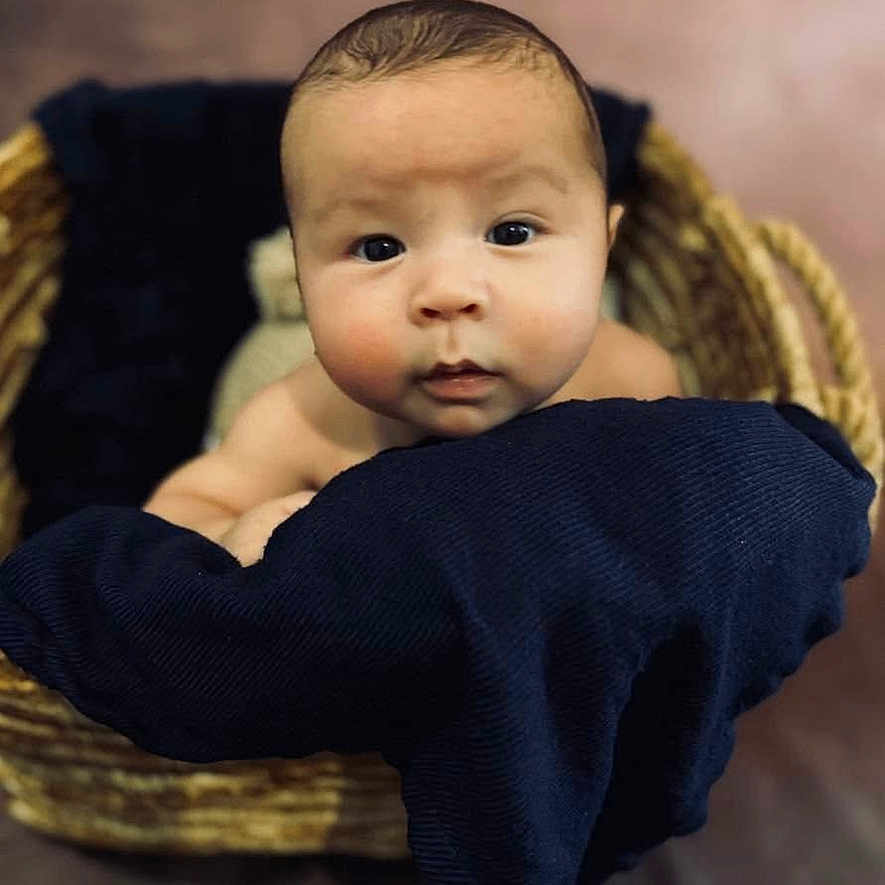 Caleb is registered to the contest to win money with this photo: baby, basket, blanket, child, closeup, cozy, curious, cute, expression, face, head, indoors, infant, newborn, person, portrait, resting, skin, soft, young
