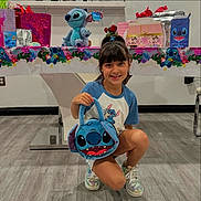 Liah is registered to the contest to win money with this photo: bag, child, clothing, face, female, girl, hair, head, indoors, person, photography, portrait, racket, shorts, sitting, sleeve, sport, t_shirt, tennis, tennisracket