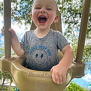 Banks joined the competition — help win amazing prizes! toddler, child, swing, playground, outdoor, happy, smile, wet_hair, shirt, gray_shirt, text_on_shirt, trees, blue_sky, daylight, play, baby, person, fun, joy, park