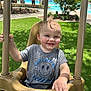 Banks is registered to the contest to win money with this photo: toddler, child, swing, playground, smiling, wet_hair, outdoor, grass, tree, pool, sunlight, shirt, person, happy, seat, hand, nature, daytime, game_time, recreation