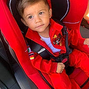 John participe au concours pour gagner de l'argent avec cette photo : child, toddler, car_seat, red_clothing, seatbelt, car_interior, looking_away, racing_patch, young_child, sitting, safety_harness, cute, portrait, casual, daylight, vehicle, young_boy, curious_expression, indoors, seat