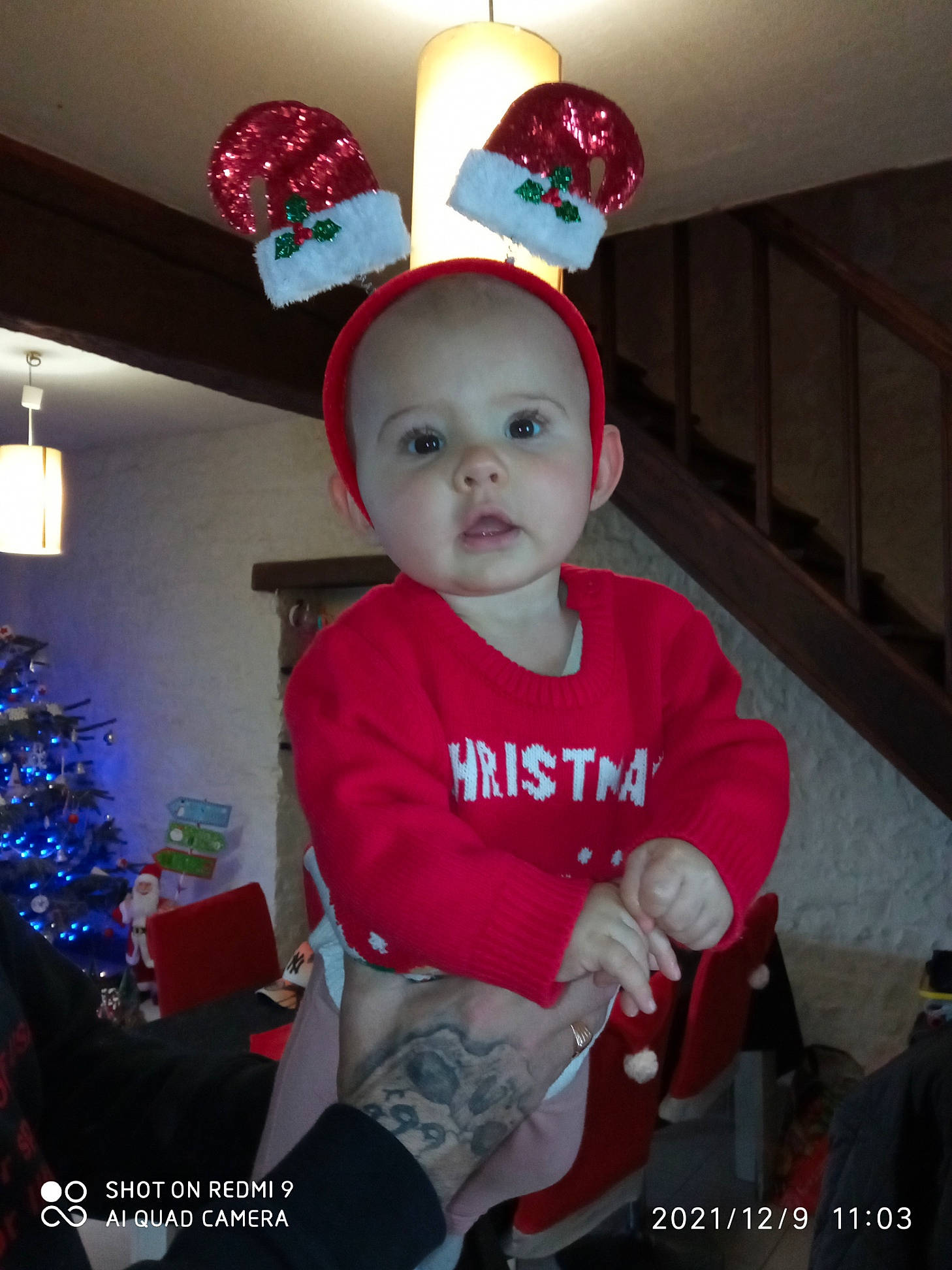 Luna participe au concours pour gagner de l'argent avec cette photo : baby, baby_toddler_clothing, cap, carmine, child, christmas, christmas_eve, christmas_tree, costume, costume_hat, event, fashion_accessory, fictional_character, fun, happy, holiday, lap, person, sleeve, t_shirt