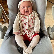 Rose a rejoint le concours — aidez-le/la à gagner de superbes lots ! baby, smiling, infant, baby_seat, headband, cream_clothing, red_clothing, tiled_floor, indoor, furniture, happy, cute, child, person, portrait, sitting, cozy, floor, baby_girl, apparel