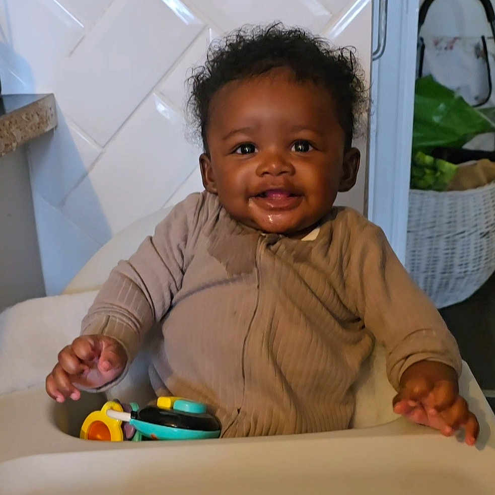 Kiki joined the competition — help win amazing prizes! baby, child, cozy_clothing, cute, expression, face, furniture, hand, happy, high_chair, home, indoor, infant, kitchen, person, playtime, seat, smiling, toy, young_child