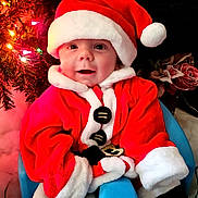 Jacob joined the competition — help win amazing prizes! baby, child, santa_claus, christmas, holiday, festive, red_clothing, hat, smile, face, chair, indoor, decorations, tree, lights, cute, portrait, happy, seasonal, warm