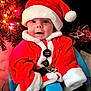 baby, child, santa_claus, christmas, holiday, festive, red_clothing, hat, smile, face, chair, indoor, decorations, tree, lights, cute, portrait, happy, seasonal, warm