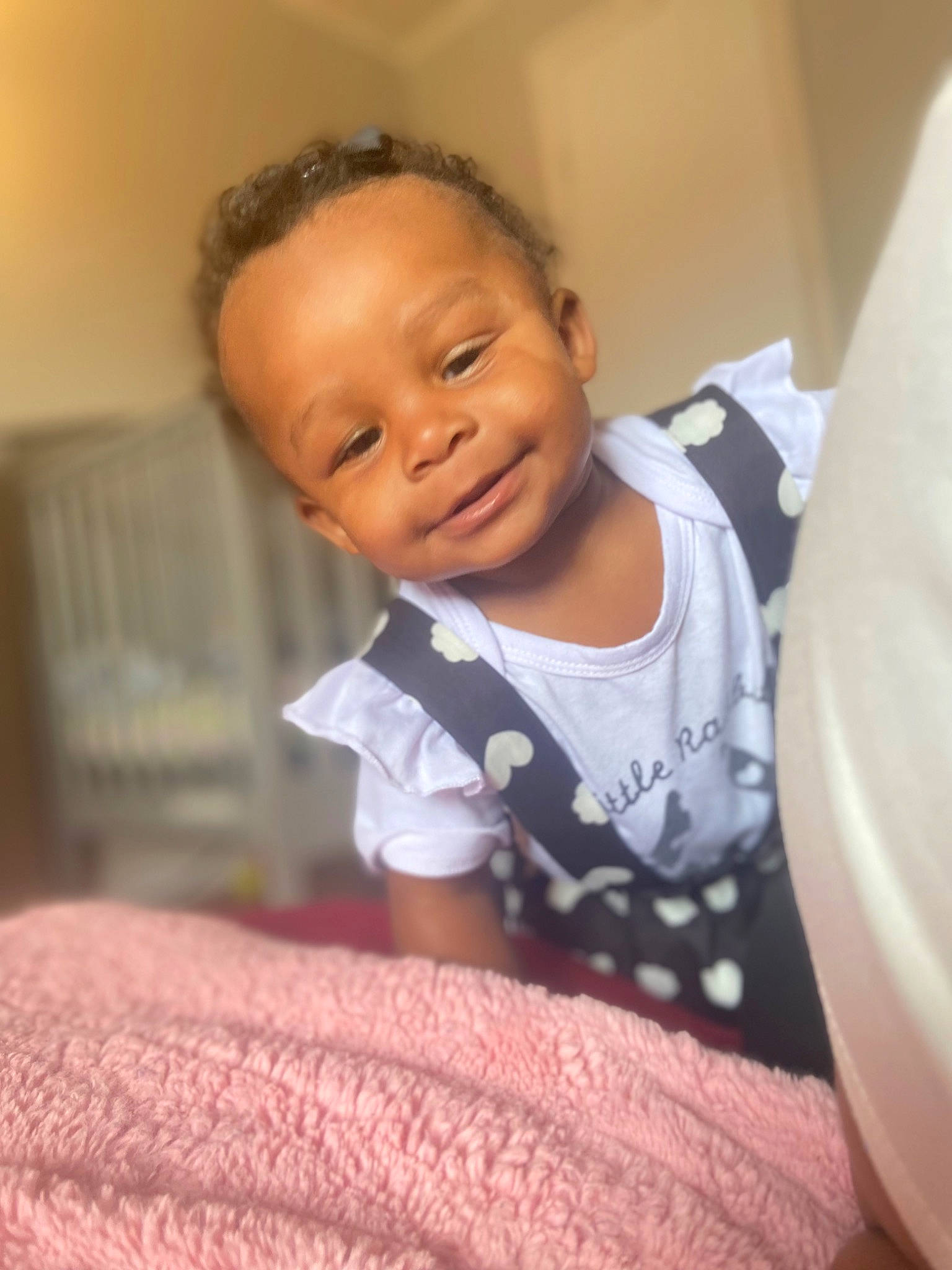Luna is registered to the contest to win money with this photo: baby, baby_toddler_clothing, bedding, cheek, comfort, elbow, face, flooring, fun, happy, joy, linens, mouth, neck, nose, person, room, sitting, sleeve, smile