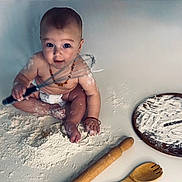 Kai joined the competition — help win amazing prizes! baby, child, clock_design, cute, diaper, face, floor, flour, foot, hands, indoor, kitchen_utensils, messy, necklace, playful, rolling_pin, sitting, whisk, wooden_board, wooden_spoon