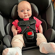 Nova joined the competition — help win amazing prizes! baby, child, car_seat, seat_belt, pink_shirt, socks, infant, smile, face, head, sitting, safety, restraint, cute, indoor, clothing, person, young_child, comfort, car_interior