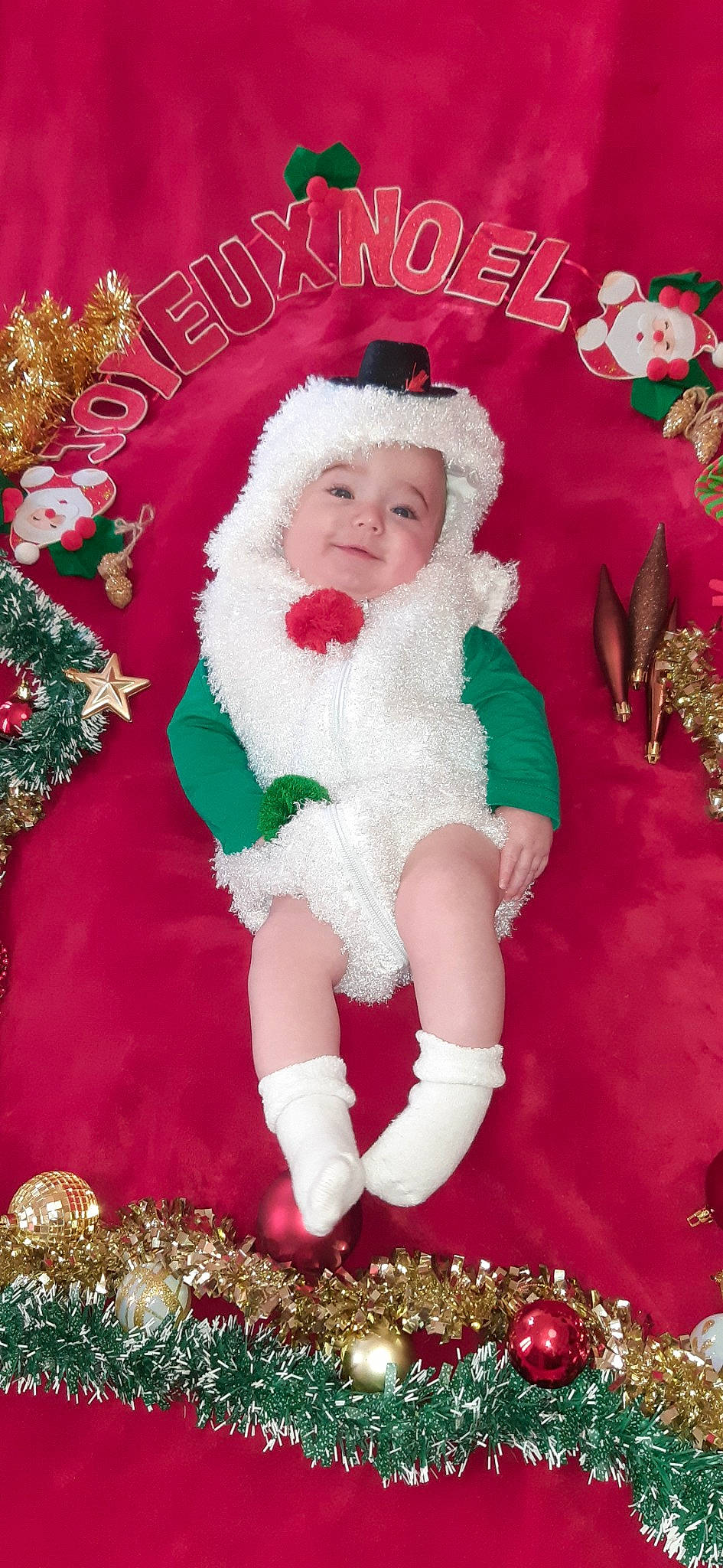 Noé participe au concours pour gagner de l'argent avec cette photo : child, christmas, christmas_eve, christmas_ornament, christmas_tree, fictional_character, fur, headwear, holiday, person, santa_claus, toddler