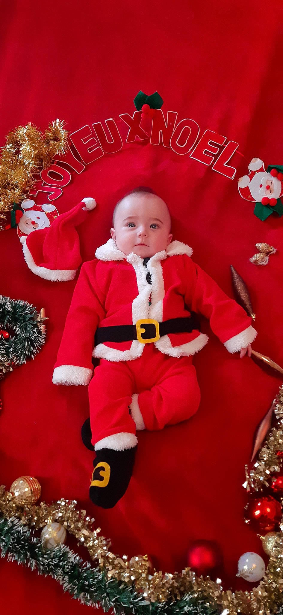 Noé participe au concours pour gagner de l'argent avec cette photo : child, christmas, christmas_decoration, christmas_eve, christmas_ornament, fictional_character, holiday, person, red, santa_claus, toddler