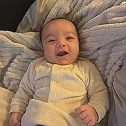 Ishaq participe au concours pour gagner de l'argent avec cette photo : baby, blanket, child, clothing, comfort, cozy, cute, drool, face, happy, indoor, infant, lying_down, pajamas, person, resting, smile, soft_texture, warm, young