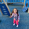 child, playground, blue, curly_hair, plaid_shirt, pink_pants, socks, outdoor, play_equipment, climbing_structure, rubber_flooring, daylight, person, recreation, fun, young, casual_clothing, looking_up, park, happy