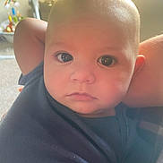Jonathan is registered to the contest to win money with this photo: baby, infant, child, face, eyes, arm, onesie, blue_clothing, portrait, close_up, indoors, toy, soft_light, skin, head, expression, relaxed, young, person, cute
