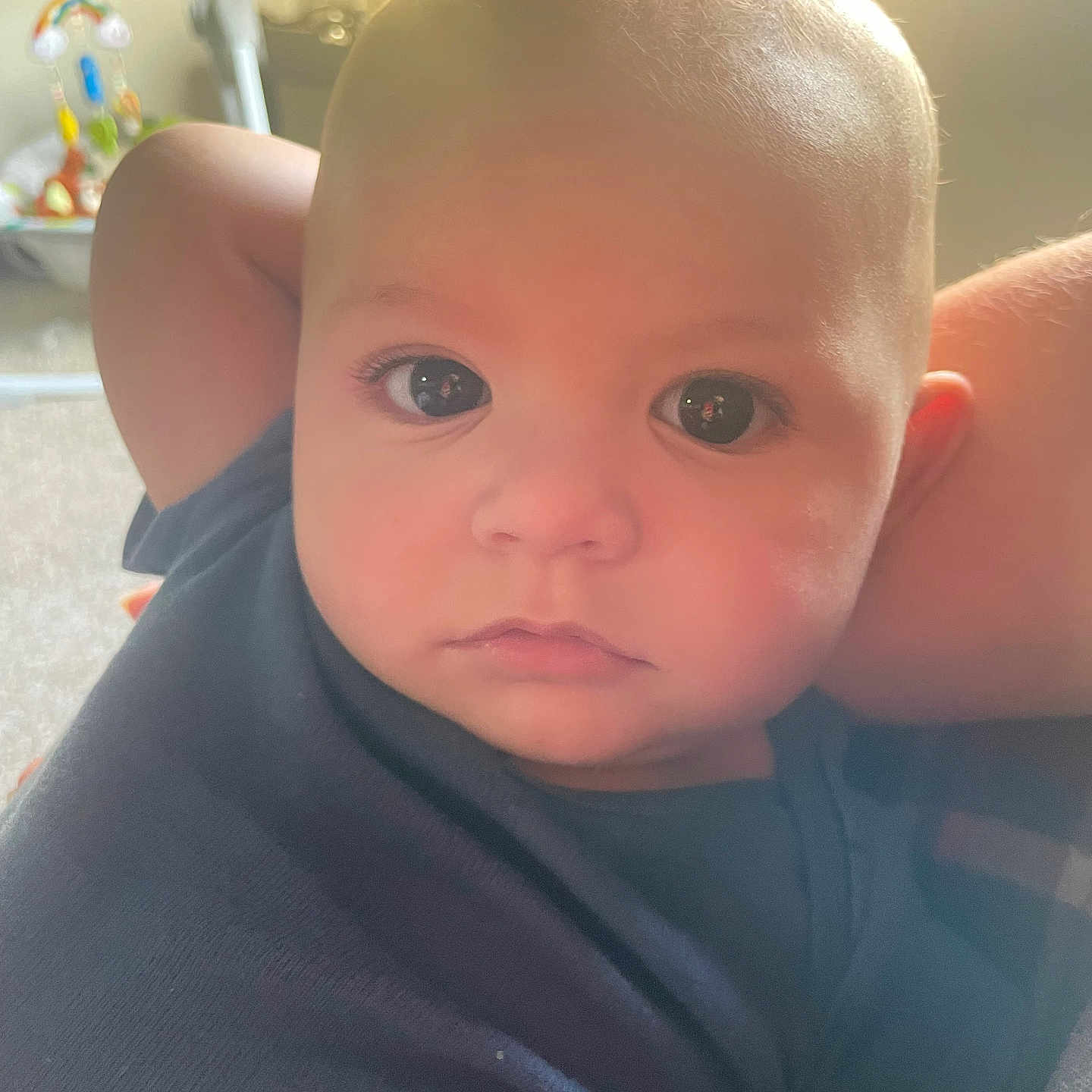 Jonathan is registered to the contest to win money with this photo: baby, infant, child, face, eyes, arm, onesie, blue_clothing, portrait, close_up, indoors, toy, soft_light, skin, head, expression, relaxed, young, person, cute