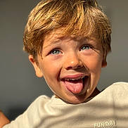 Lucas a rejoint le concours — aidez-le/la à gagner de superbes lots ! child, boy, smiling, tongue_out, blond_hair, blue_eyes, close_up, portrait, casual_clothing, tshirt, sunlight, happy, playful, indoors, face, expression, young, skin, person, fun