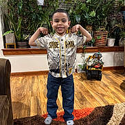 Josiah Antonio is registered to the contest to win money with this photo: child, boy, smiling, flexing, spiderman_jersey, jeans, socks, indoor, wood_floor, colorful_rug, plants, greenery, toy_truck, dinosaurs, window_blinds, wood_trim, living_room, happy, playful, portrait