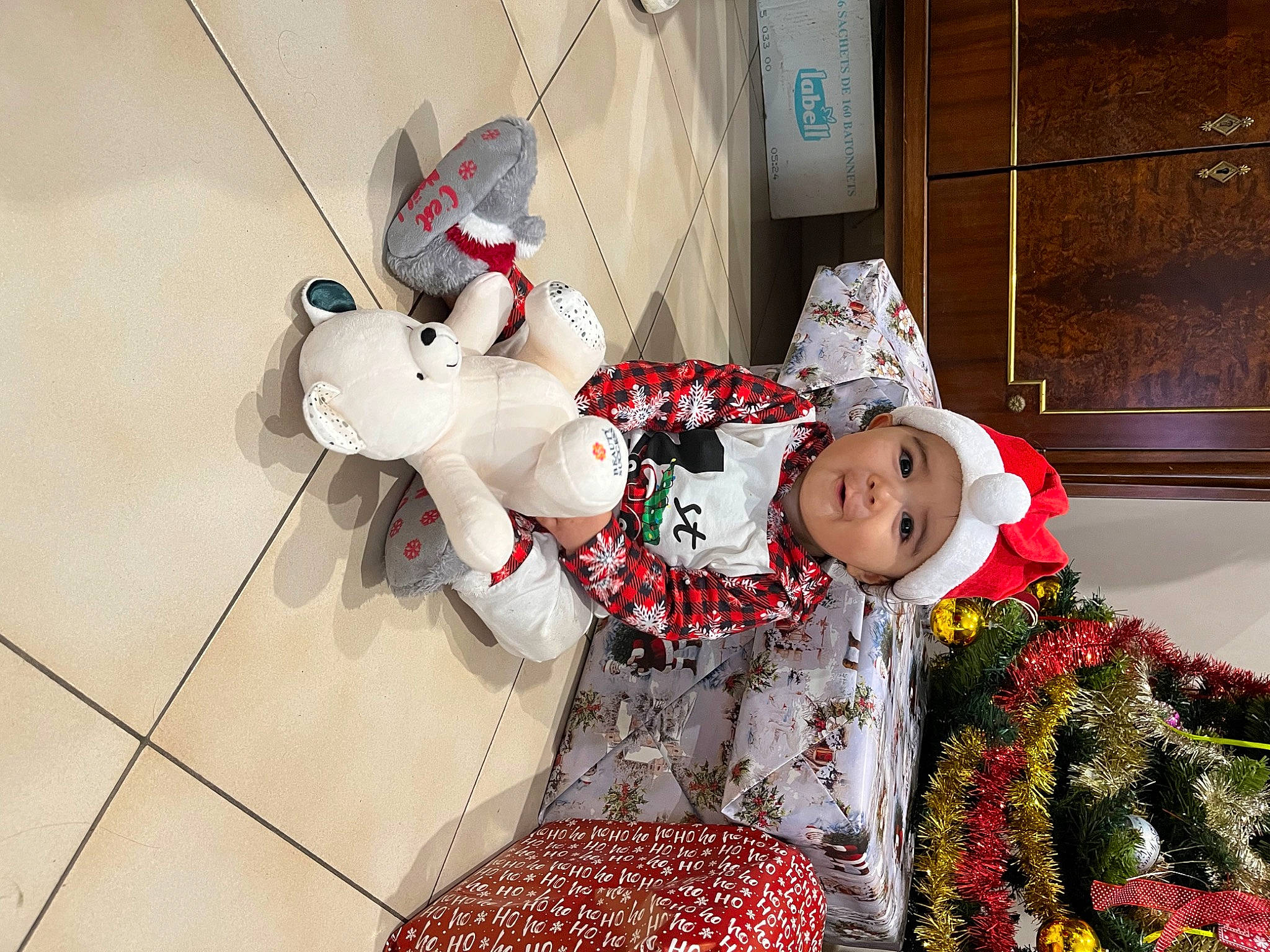 Nathan participe au concours pour gagner de l'argent avec cette photo : baby_toddler_clothing, carmine, child, christmas_decoration, christmas_ornament, comfort, costume_hat, event, fictional_character, happy, hat, headwear, holiday, lap, ornament, person, plant, room, santa_claus, toddler