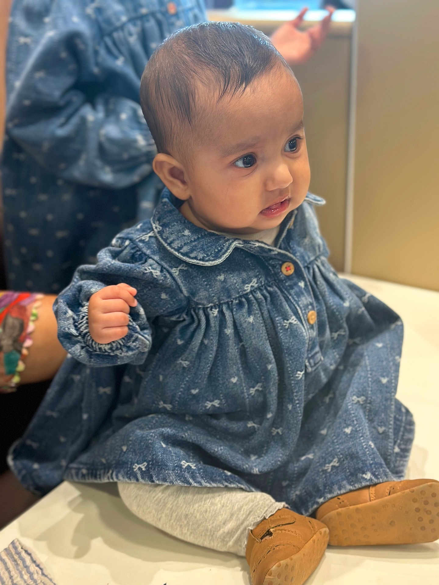 Gurrehmat is registered to the contest to win money with this photo: baby, denim_dress, blue, sitting, cute, child, shoes, leggings, expression, indoor, curious, hand, face, portrait, clothing, apparel, person, young_child, soft_lighting, blurred_background