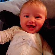 Dilylah is registered to the contest to win money with this photo: baby, smiling, infant, onesie, cute, happy, child, face, portrait, lying_down, cozy, soft, patterned_clothing, young_child, indoors, head, cheerful, skin, baby_clothes, closeup