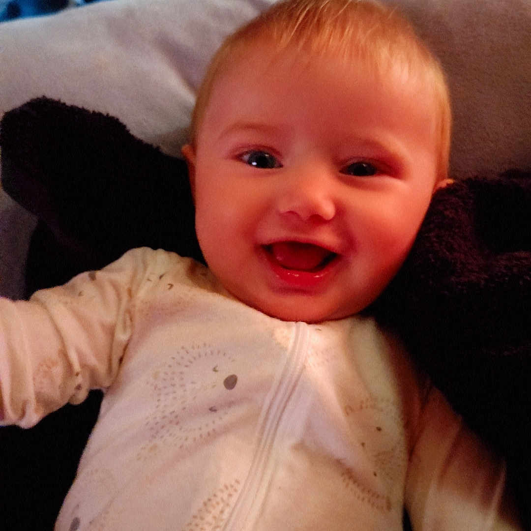 Dilylah is registered to the contest to win money with this photo: baby, baby_clothes, cheerful, child, closeup, cozy, cute, face, happy, head, indoors, infant, lying_down, onesie, patterned_clothing, portrait, skin, smiling, soft, young_child