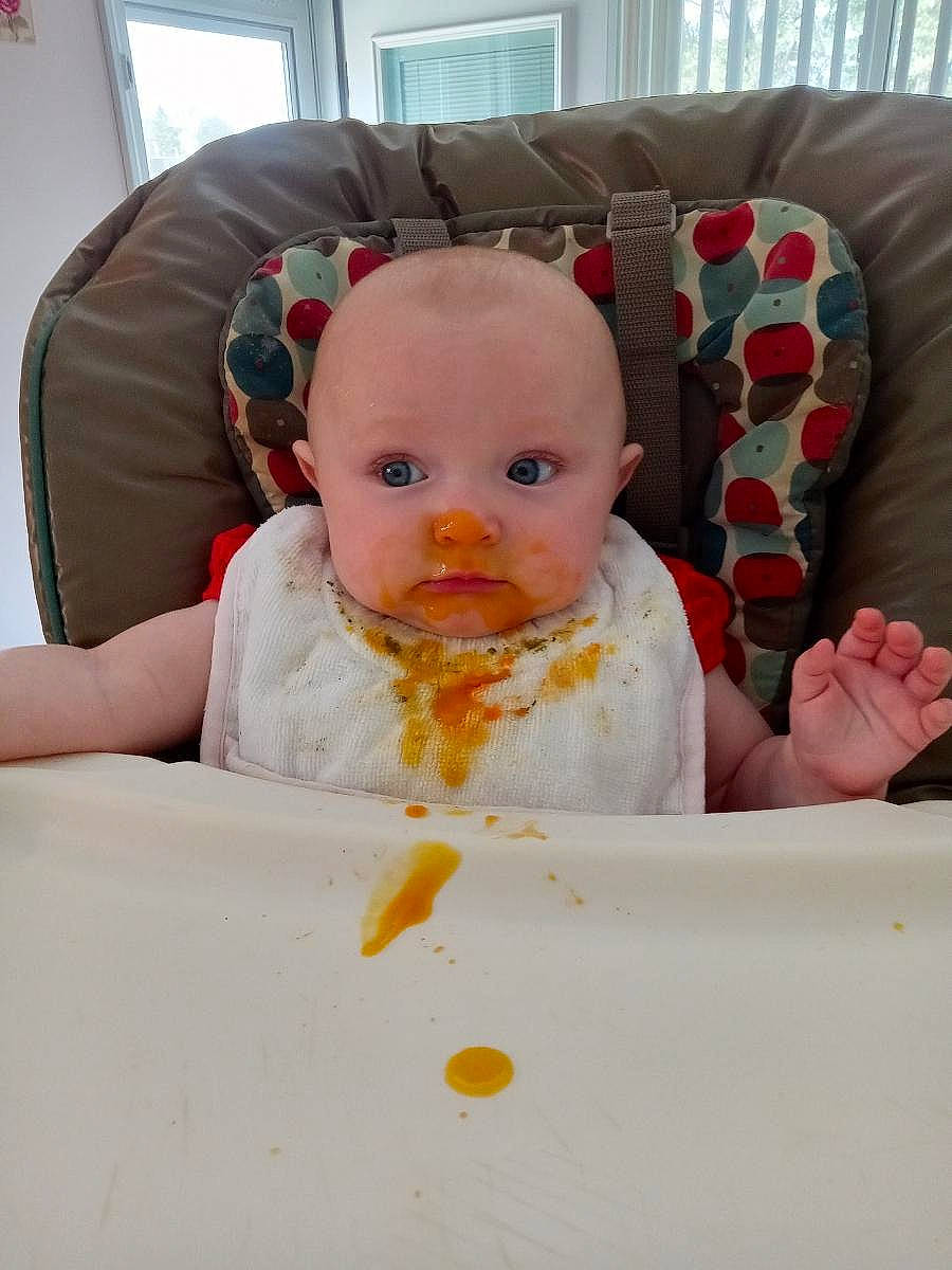 Lucy is registered to the contest to win money with this photo: baby, baby_toddler_clothing, bib, chair, cheek, child, comfort, comfort_food, couch, cuisine, dish, dishware, drinkware, hairstyle, person, plate, porcelain, serveware, sitting, tableware