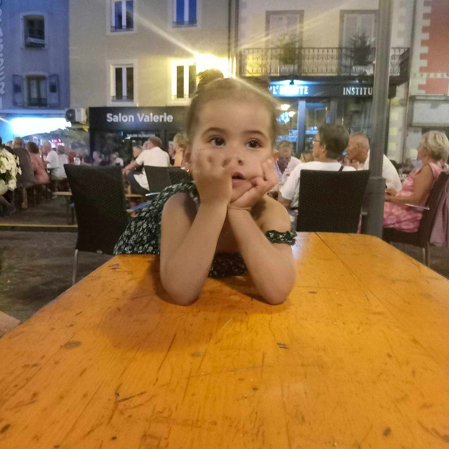 Alya Acerbis participe au concours pour gagner de l'argent avec cette photo : building, cafe, casual, chairs, child, contemplative, dress, evening, girl, light, outdoor, people, portrait, public, relaxed, resting, social, table, urban, wood