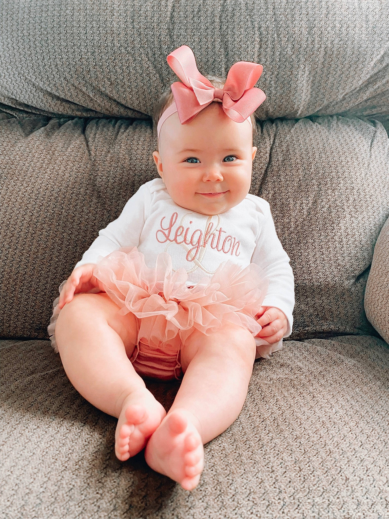 Leighton is registered to the contest to win money with this photo: arm, baby, baby_toddler_clothing, cap, comfort, costume_hat, couch, eye, face, finger, hand, head, headwear, human_body, human_leg, joy, person, pink, skin, sleeve