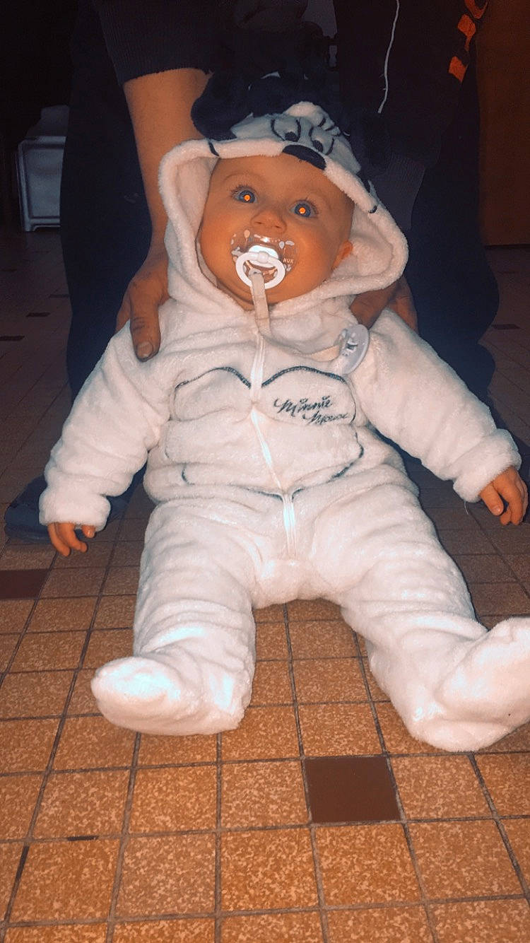 Ylianna participe au concours pour gagner de l'argent avec cette photo : baby, baby_toddler_clothing, carmine, cheek, child, comfort, costume, eye, flooring, fun, fur, hat, head, headgear, headwear, nose, person, personal_protective_equipment, sitting, skin