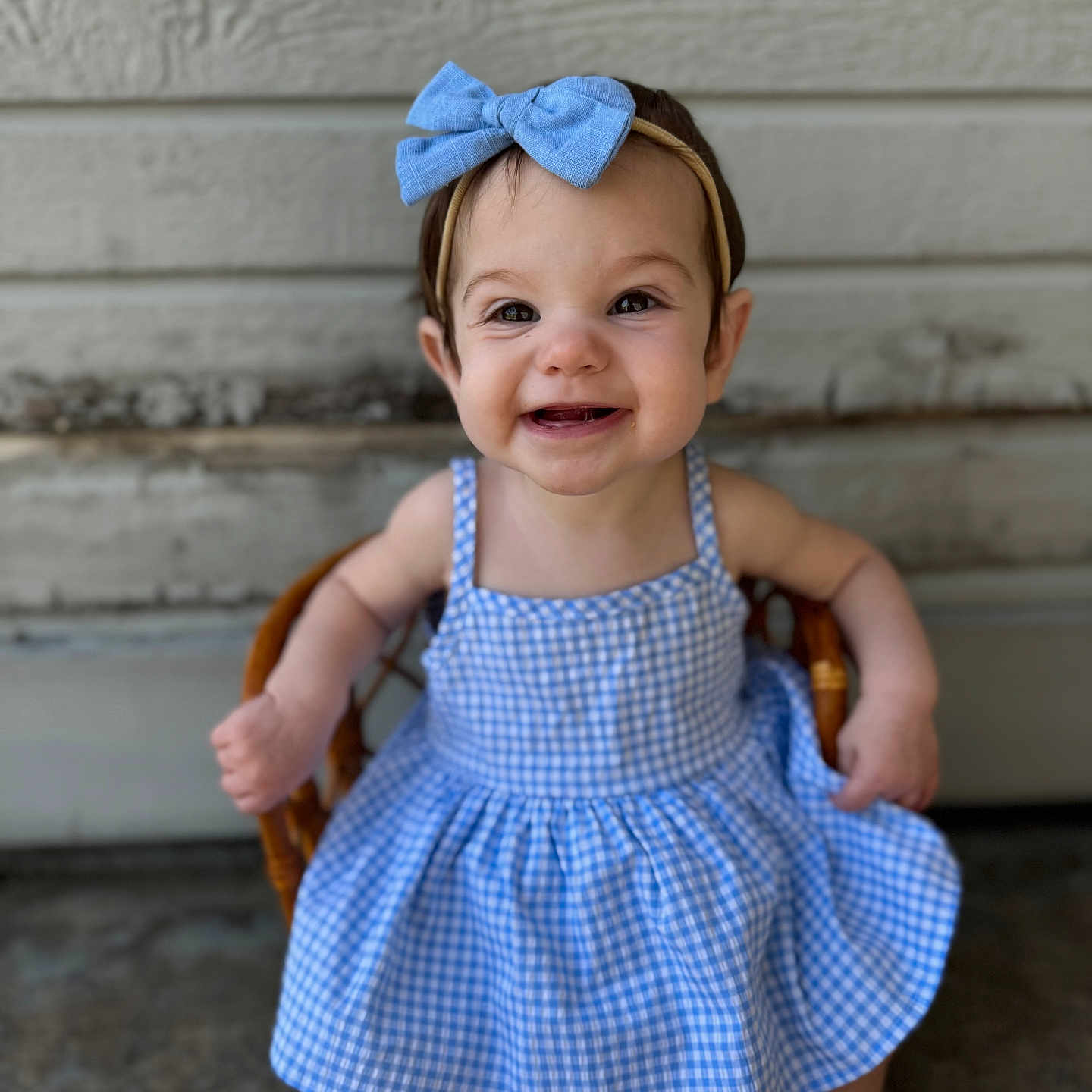 Salem joined the competition — help win amazing prizes! baby, background, blue_bow, child, clothing, cute, fashion, gingham_dress, happy, headband, headwear, outdoor, person, portrait, sitting, smiling, toddler, wicker_chair, wooden_wall, young_child