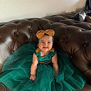 Genesis joined the competition — help win amazing prizes! baby, child, smiling, dress, headband, bow, green_dress, gold_accents, couch, leather, indoor, happy, sitting, cute, portrait, plush, tulle, fashion, person, infant