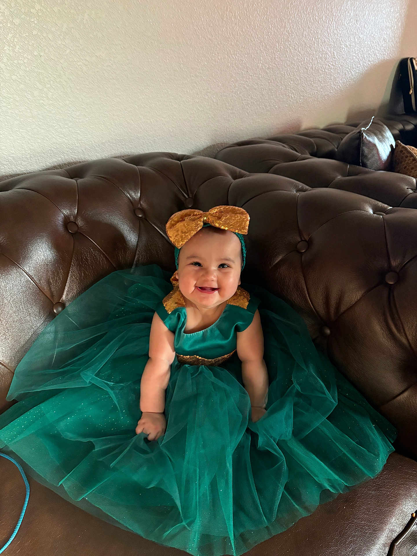 Genesis joined the competition — help win amazing prizes! baby, child, smiling, dress, headband, bow, green_dress, gold_accents, couch, leather, indoor, happy, sitting, cute, portrait, plush, tulle, fashion, person, infant